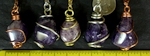 Amethyst tumbled stones wire wrapped as pendants on necklaces. Amethyst is the purple form of quartz. They vary in color from lavender to dark purple, and are mostly translucent