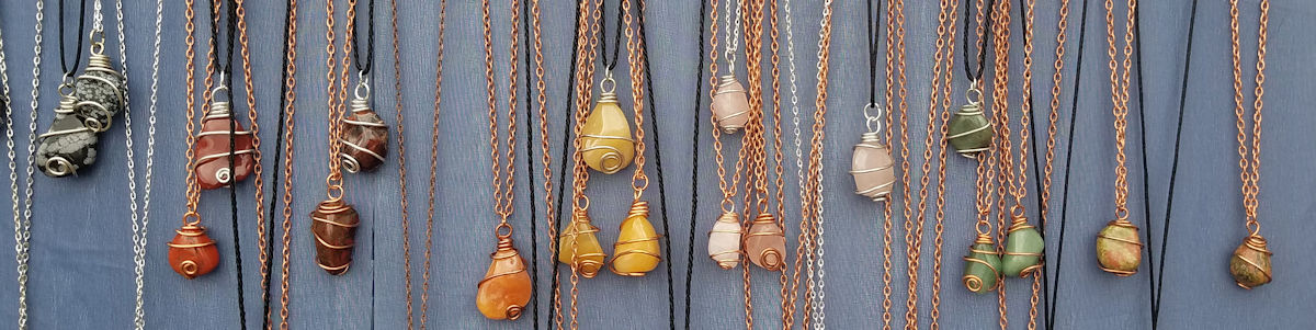 Handmade wire wrapped crystal and tumbled stone necklaces hanging in a row